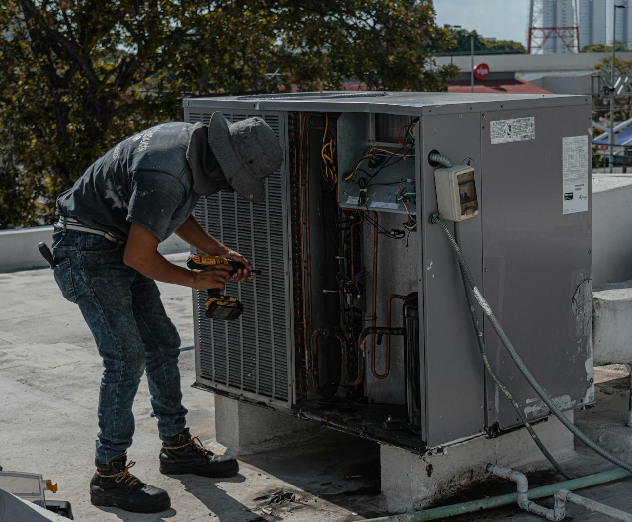 Mastering the First Impression: Your intriguing post title goes here A worker in a bucket hat repairs an outdoor air conditioning unit on a rooftop.